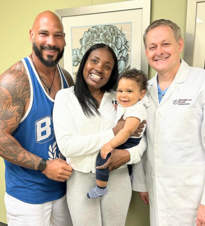 Dr. Martinez smiles next to a happy couple and their RSCNJ baby