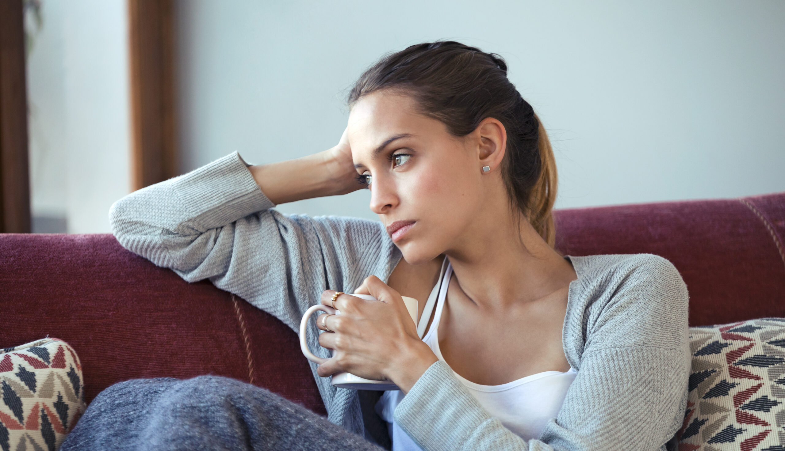 concerned woman sitting on her couch thinking about ectopic pregnancy | Reproductive Science Center of New Jersey | Eatonville, Toms River & Lawrenceville